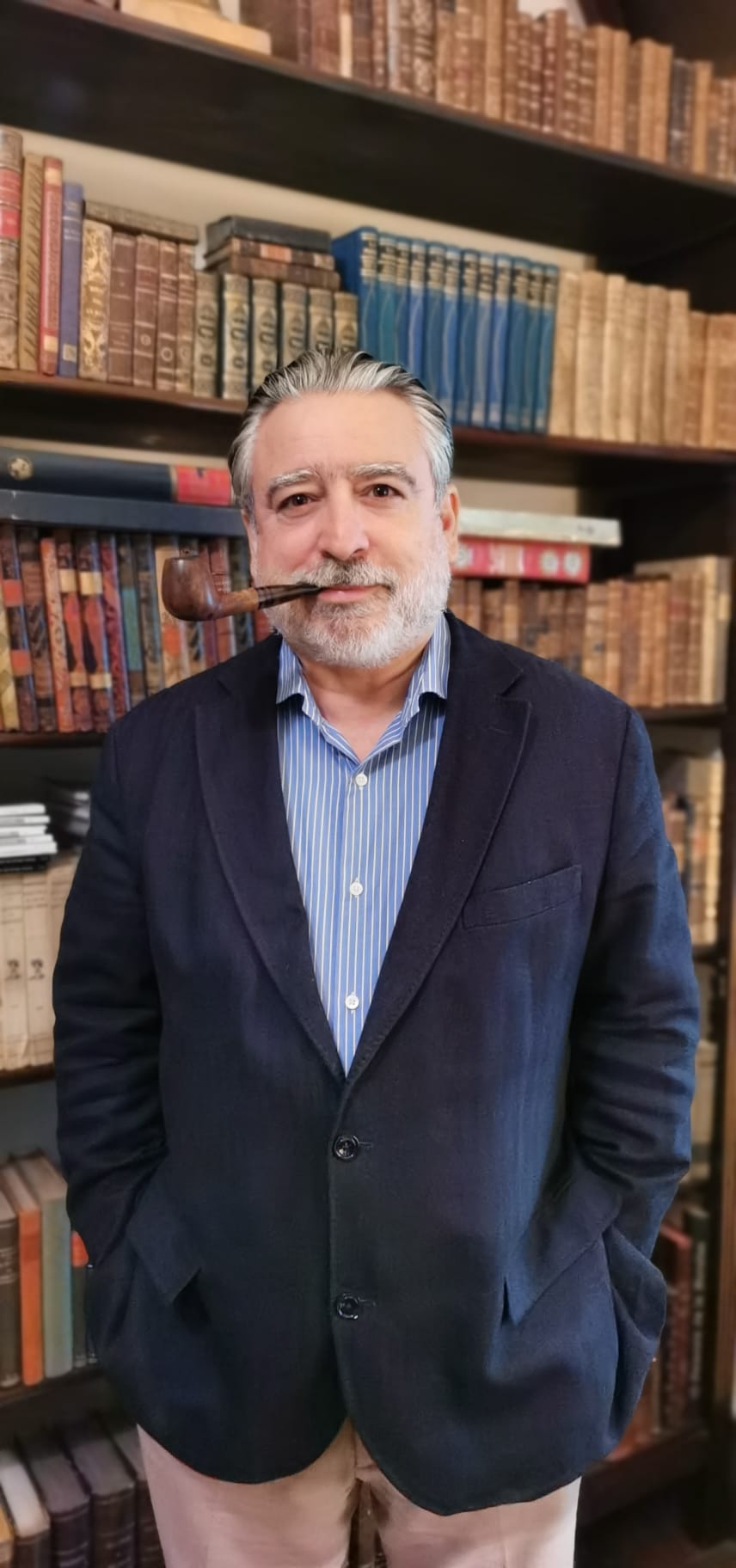 Hombre mayor con pipa en biblioteca